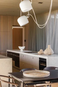 A modern kitchen with concrete countertops and wooden cabinets, featuring a central island with a white bowl and woven basket