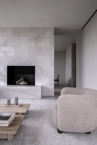 A modern living room with a concrete fireplace and a textured armchair.
