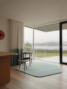 Modern living room interior with glass walls, wooden floor, and rug.