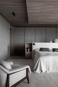 A modern, minimalist bedroom featuring metallic gray textures and a large bed with grey linens.