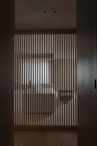 A view of a minimalist bedroom with a wooden room divider.