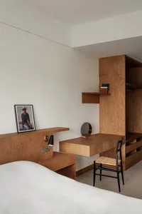 A minimalist bedroom with wooden furniture and a white bedspread.