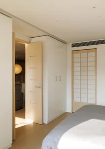 A minimalist bedroom featuring wooden paneling and a bed with white linens.