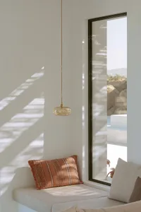 A minimalist window seat relaxation space featuring a glass coffee table and natural light.