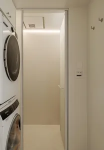 Modern laundry room with glass sliding door, featuring a sleek design and minimalistic aesthetic.