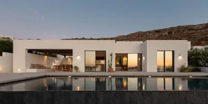 A modern residential exterior with concrete walls and a pool at dusk.