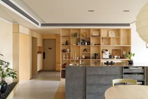 A modern residential kitchen with a gray countertop island and wooden shelves