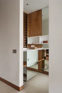 A modern bathroom with wooden walls and a white countertop, featuring a sink and a mirror.