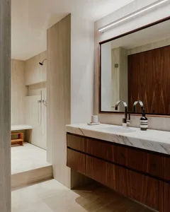 Modern minimalist bathroom featuring marble countertops and wooden cabinets.