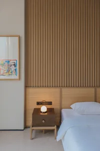 A minimalist bedroom with a wooden panel wall and a neatly made bed.