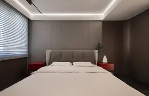 A modern bedroom with a white bed and red side tables.