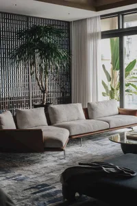 Modern living room featuring fabric and leather furniture with a potted plant in the corner.