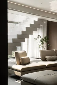 Modern living room with cream-colored leather furniture, glass staircases, and white curtains.
