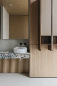 Modern minimalist bathroom with a white circular sink, granite countertop, and wooden textured paneling.