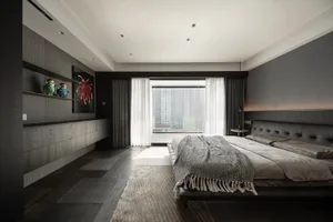 Modern minimalist bedroom featuring taupe-colored fabric and furniture, large window with white curtains, and a large black h