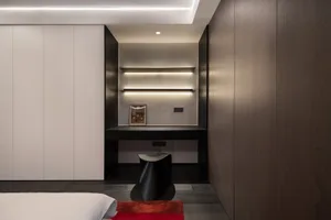 A modern minimalist bedroom with wooden walls, shelves, and a desk with a stool underneath.
