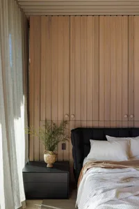 Minimalist bedroom featuring wooden walls, black furniture, and white bedding.