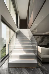 Modern staircase with glass railing and marble steps.