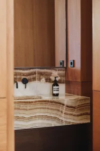 A minimalist bathroom with a marble countertop, black fixtures, and a bottle of Aesop lotion.