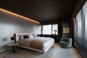 A minimalist bedroom featuring a fabric bed and modern furnishings.