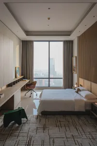 A minimalist bedroom with a grey bed and curtains, large window, and modern furniture.