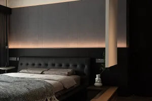 A minimalist bedroom with black textured paneling, concrete floor, and modern furnishings.