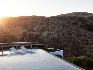 Minimalist outdoor spa area with concrete structures against a rocky mountain backdrop.