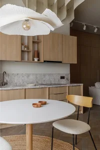 Modern kitchen with minimalist design, featuring wooden cabinets and a marble countertop.