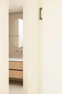 Modern bathroom with floating wooden cabinets and metallic fixtures.