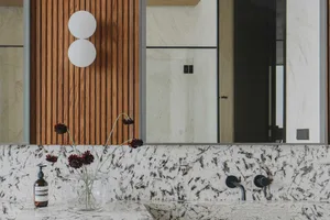 Modern bathroom featuring a luxurious granite countertop with a minimalist sink and sleek metallic faucet, illuminated by a c