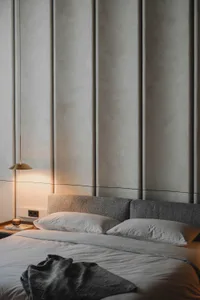 Modern bedroom featuring grey fabric bedding and a grey upholstered headboard against a neutral wall.