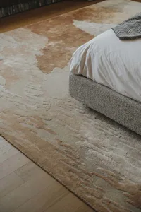A modern bedroom featuring a textured suede rug with an abstract design.