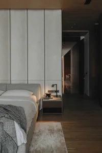 A modern bedroom with a taupe upholstered bed and a wooden nightstand.
