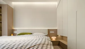 A modern bedroom featuring a white interior with wooden detailing and a white bed with striped bedding.