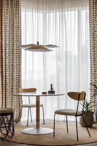 Modern dining room featuring minimalist design, wooden chairs, round table, and geometric curtains.