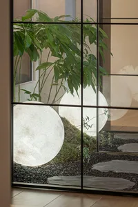 Modern interior design featuring stone and plants illuminated by spherical lamps.