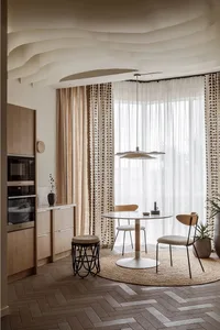 A modern kitchen featuring a wooden table and chairs near a window with patterned curtains and herringbone-patterned flooring