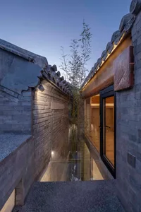A narrow passage with tiled walls, brick and concrete structures, and traditional Chinese roofing tiles