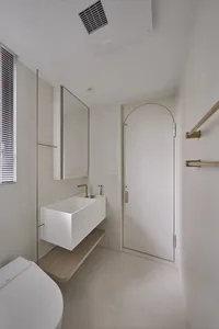 Modern minimalist bathroom with concrete sink, brass fixtures, and a white toilet.
