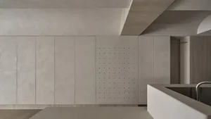 A minimalist interior space featuring concrete wall panels with perforated holes.
