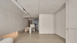 A minimalist kitchen with concrete finishes and a central dining table.