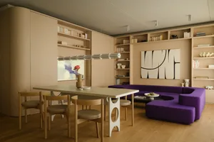 A minimalist living room featuring wooden furniture, bookshelves, and a purple sofa.