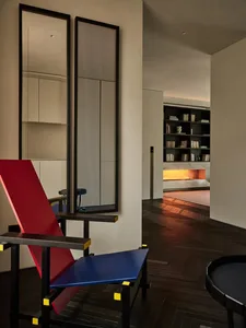 A modern living room with a metal construction featuring a red and blue geometric chair.