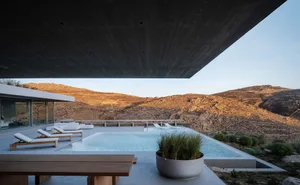 Modern luxury house with concrete pool and view of rugged landscape