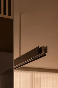 Modern metallic wardrobe detail showcasing sleek design and minimalist aesthetics against warm brown background.