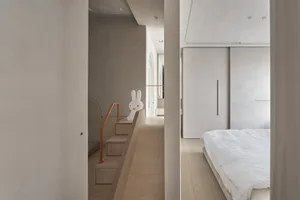 簡約臥室內有白色床鋪與木質地板。