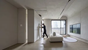 A minimalist living room featuring a white sofa and concrete floors and walls.