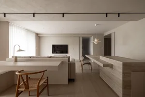 A modern minimalist living room with concrete finishes, a flat-screen TV, and a dining area with a wooden table and chairs.