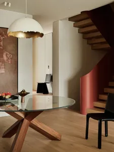 Modern minimalist dining room featuring a glass table and wooden stairs.