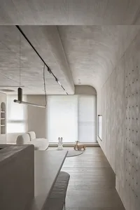 A modern minimalist living room featuring a concrete floor, white furniture, and simple decor.